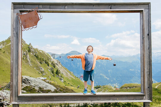 Boy standing with arms outstretched inside wooden frame