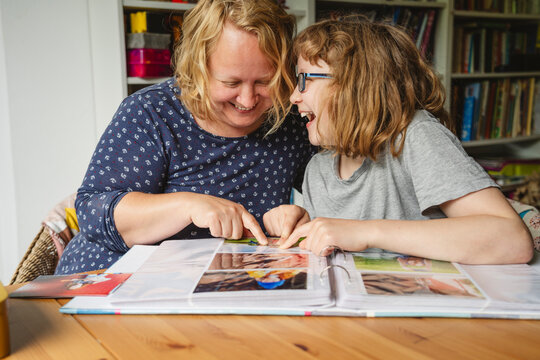Cheerful mother and daughter looking at photographs