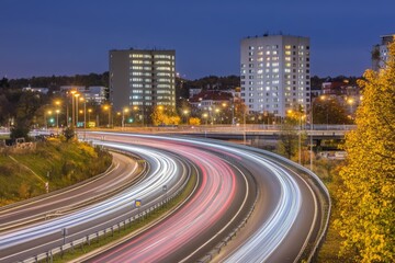 "Illuminated Freeway at Twilight: Fast Traffic and Urban Skyline Overpass in a Modern European Cityscape"