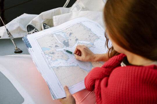 Woman preparing route using map on yacht