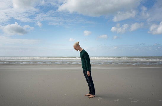 Boy leaning forward standing on sand at beach
