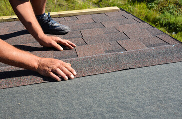 Roofing contractor lay asphalt shingles tiles on house rooftop. Asphalt shingles roofing...