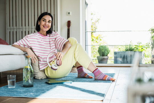 Smiling woman sitting on rug at home
