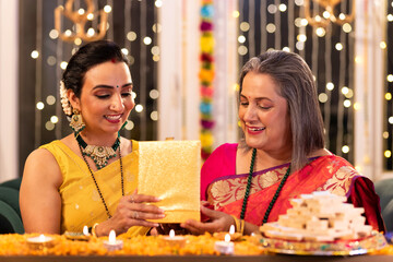 Senior mother giving Diwali gifts to daughter at home