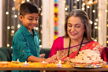 Grandmother and grandson lighting diyas at home during 