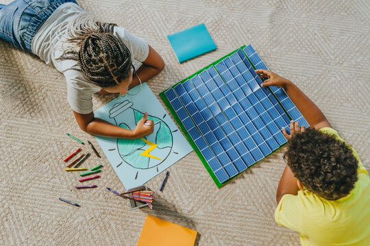Siblings working on solar energy school project on carpet