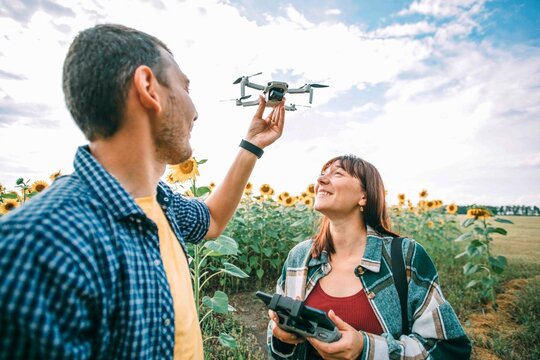 Happy couple flying drone at sunflower field