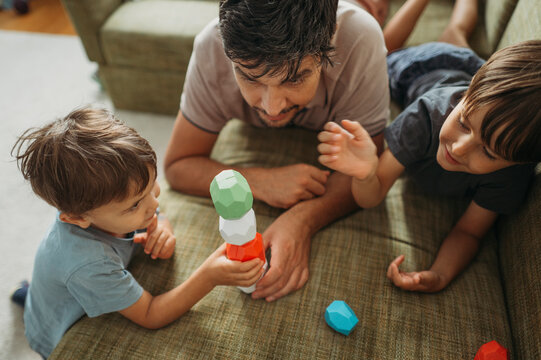 Boy building toy blocks with father and brother at home - Powered by Adobe