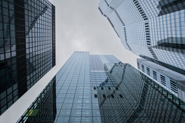 Towering skyscrapers ascending towards a cloudy sky, creating a powerful image of urban growth and the convergence of modern architecture, captured from a low angle.