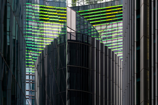 A modern cityscape featuring tall glass buildings reflecting each other in an intricate pattern of lines and colors, showcasing urban architecture and design.