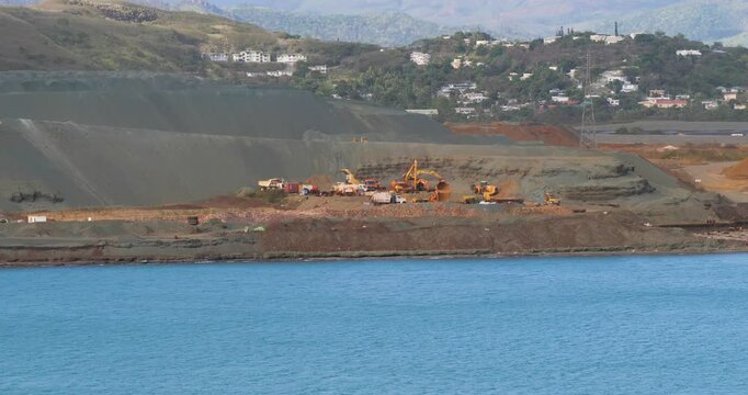 Excavators and trucks working on ore dumps at Doniambo Nickel Smelter Plant, Noumea, New Caledonia.