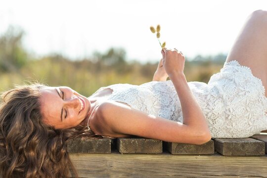 Smiling young woman holding pampas grass and lying down