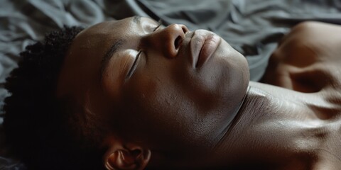 A close-up profile shot of a man with a shaved face, expressionless and resting.