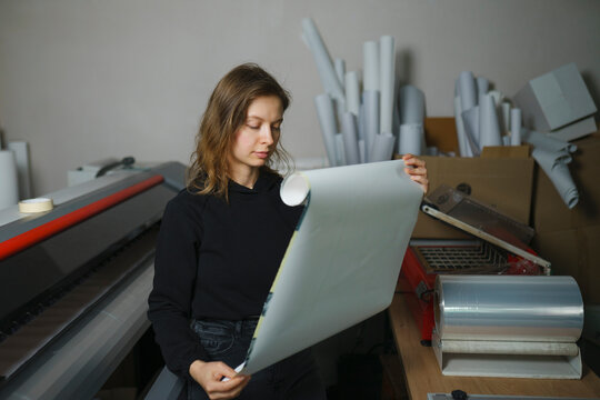 Operator holding paper roll and standing near large format printer