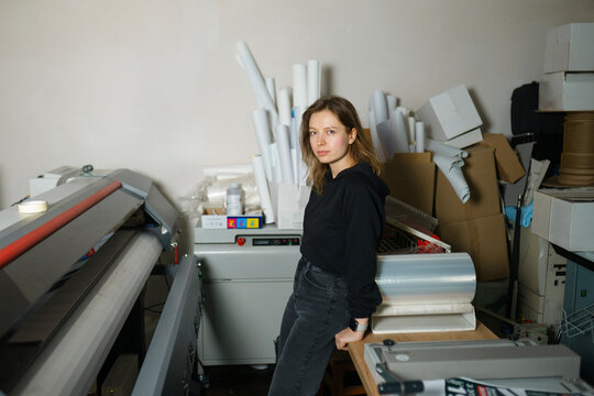 Operator leaning on table near large format printer