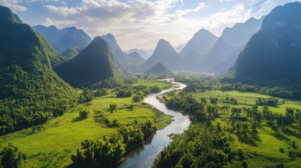 A winding river cuts through a lush green valley at the foot of towering mountains, with trees lining the landscape.