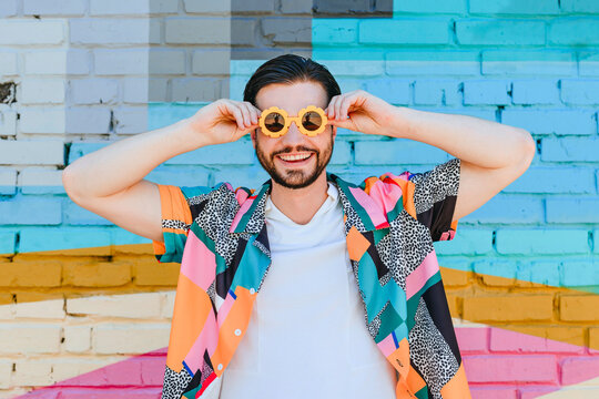 Cheerful man wearing sunglasses in front of brick wall
