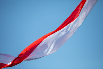 Polish flag waving in the wind against a blue sky.