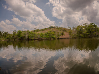 The image shows a tranquil lake with reflections, surrounded by trees under a cloudy sky