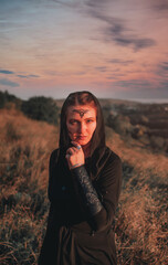 Beautiful girl in black gothic style clothes with tattoo on her face