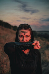 Beautiful girl in black gothic style clothes with tattoo on her face