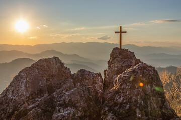 Silhouettes of crucifix symbol on top mountain with bright sunbeam on the colorful sky background