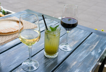 Red wine, herbal lemonade and white wine glasses on restaurant table. Family dinner in restaurant