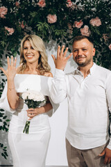 Happy Couple Celebrating Their Wedding Day with Joyful Smiles and Beautiful Floral Backdrop