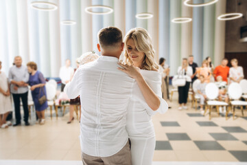 Elegant Couple Embracing at a Wedding Ceremony with Guests in Background