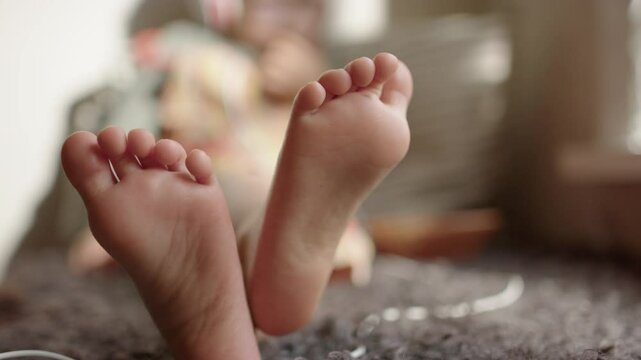 The bare feet of a 3 year old child as they relax on a sofa