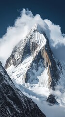 A snow-covered mountain peak rising sharply into the sky, with steep cliffs and clouds swirling around the summit