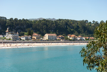 Tranquil beach scene with crowds enjoying sunny day in Asturias