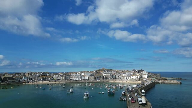 St Ives, Cornwall, England: DRONE VIEWS: Smeaton's Pier and lighthouse, St Ives Harbour and pleasure boats. St Ives is a renowned UK holiday destination and a magnet for the artist community (Clip 1).