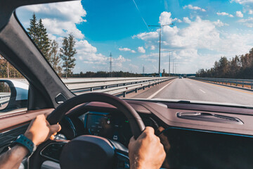 Man driving modern car from rear view on the highway. Hands on the steering wheel.