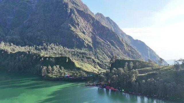 A very beautiful morning view of the lake in a tropical forest with green water, 4K drone shot with orbit motion of segara anak lakes mountain of rinjani