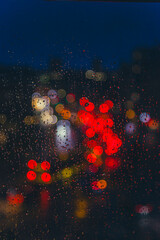 rain drops on window surface with colorful traffic bokeh light in background