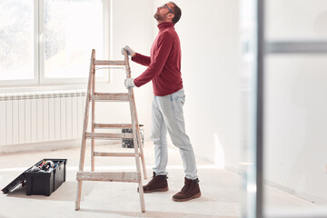 Handyman electrician with ladders working in a new home interior.