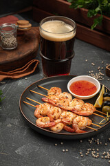 Portion of shrimp skewers with sweet and sour sauce with beer