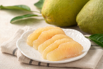 Fresh pomelo fruit with leaf on white table background.