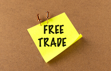 Free trade text on a yellow sticky note pinned to a corkboard with copper pushpins