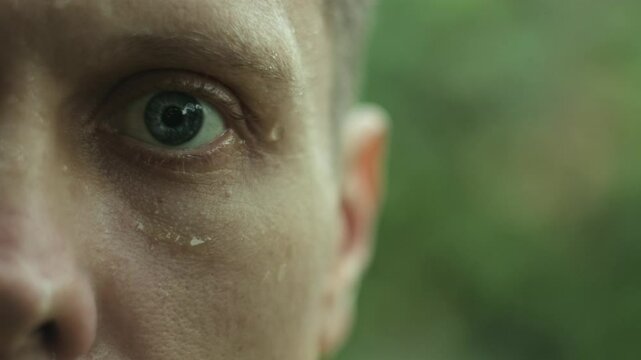 Close-up of a sad and exhausted man standing in the rain, expressing feelings of loneliness and frustration.
