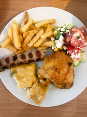 Potatoes, chicken and vegetable salad on a plate.