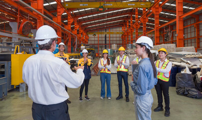 Warehouse safety meeting, people with hard hats. Industrial teamwork.