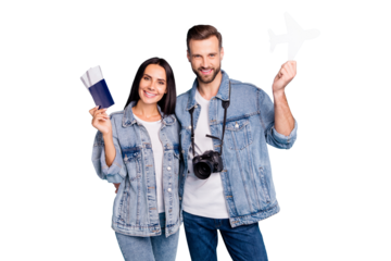 Portrait of joyful sweethearts holding passport papercard plane smiling hugging embracing wearing denim jeans isolated over blue background