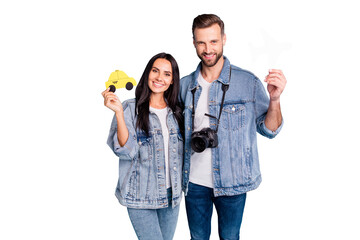 Portrait of lovely spouses holding paper card plane and taxi camera wearing denim jeans jackets isolated over blue background