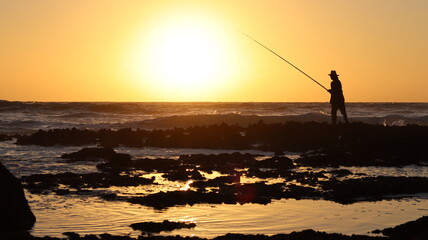 Silhouette of Fisherman at Sunset, Man Fishing on Rocky Shore, Ocean Fishing Scene, Fishing Lifestyle, Coastal Fishing Photos, Sea Angler, Fishing Stock Image
