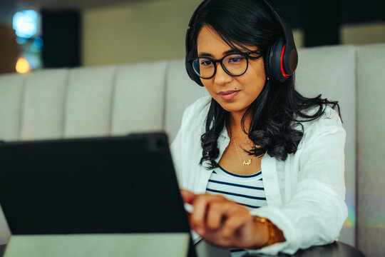 Engaged student learning with headphones on tablet in a cozy environment