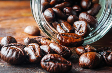 Close-up of roasted coffee beans poured out of a glass jar, Coffee beans spilled out from jar,Close up