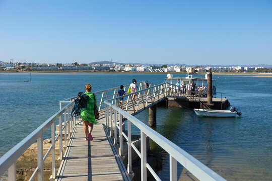 Scenic view of tourists boarding a ferry to Fuseta Island, Algarve, Portugal. The image captures a sunny day, clear skies, and tranquil waters, perfect for vacation and exploring coastal landscapes.