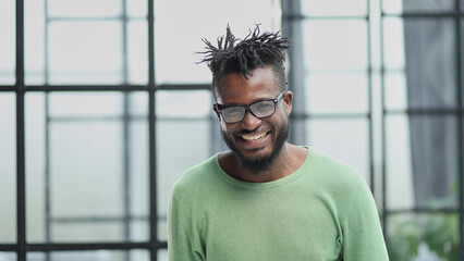 african american man in a green shirt holding his hands behind his head